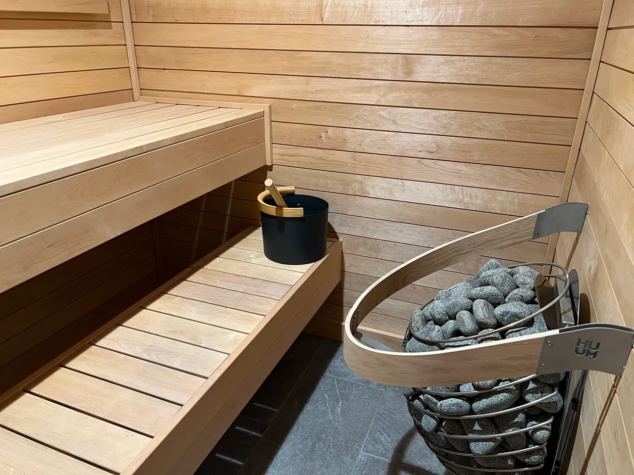 Wooden sauna benches with bucket and stone heater