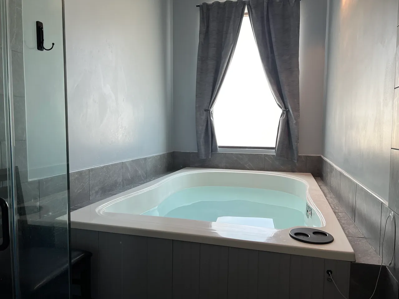 Corner soaking tub with window and curtains