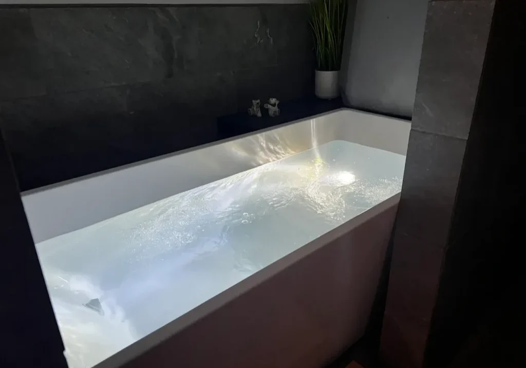 Modern bathtub filled with illuminated water