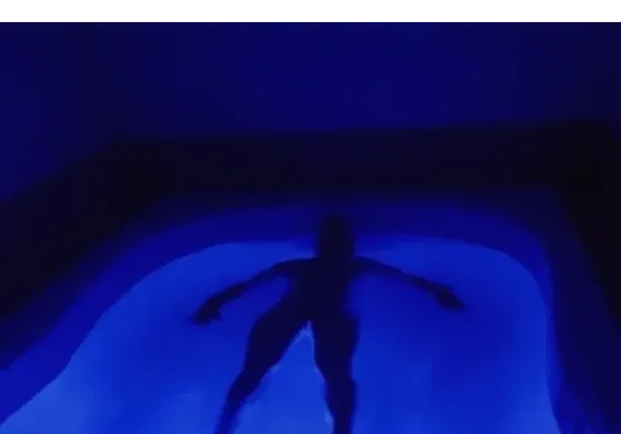 Silhouette floating in illuminated blue pool