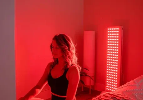 Woman meditating beside red LED light panel